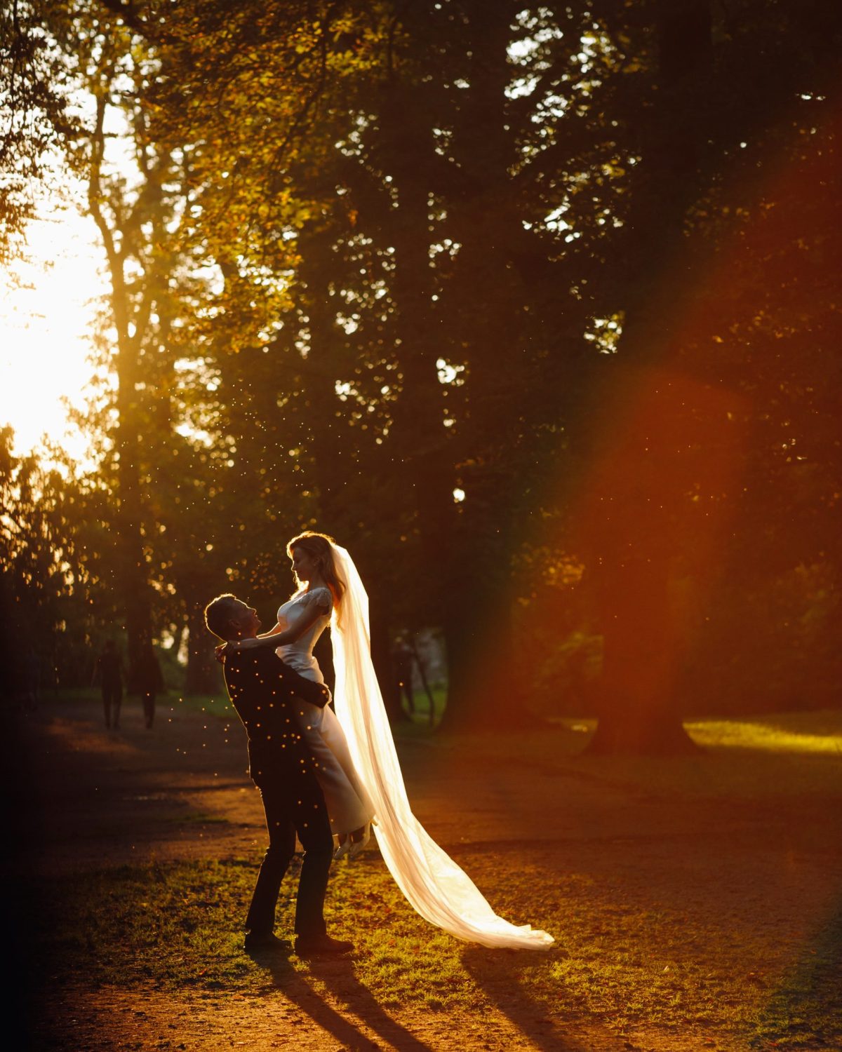 Evening summer sun makes a halo around beautiful wedding couple hugging in the park